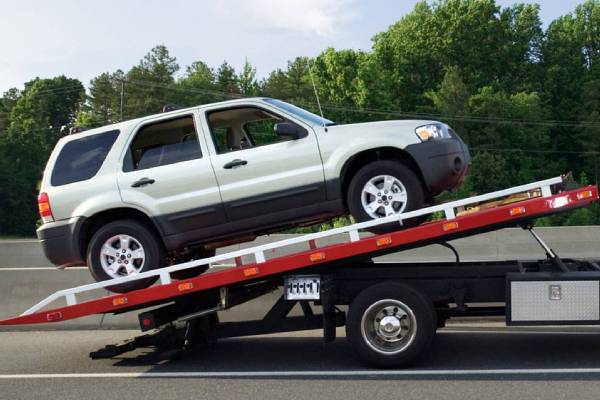 Flatbed truck providing car removal services for a white SUV