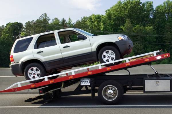 Car towing services loading SUV onto flatbed tow truck roadside