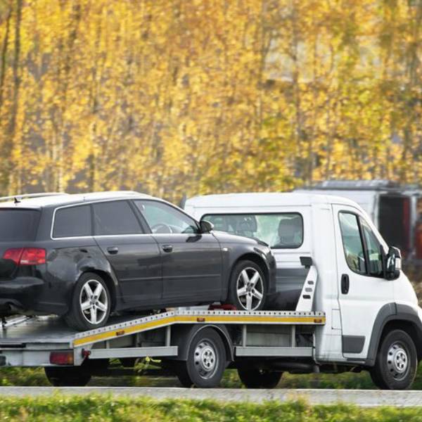Flatbed truck carrying car for reliable towing services on road