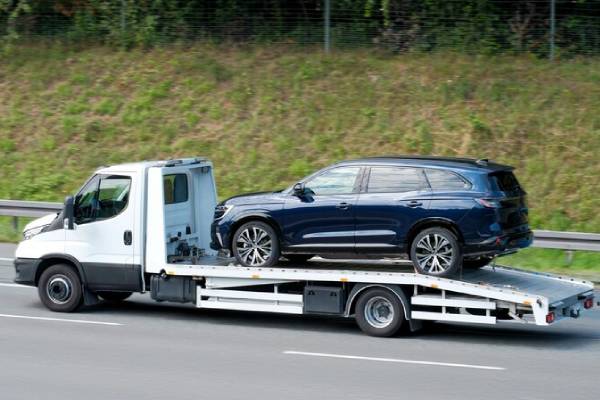 Tow truck transporting van on highway with professional towing services