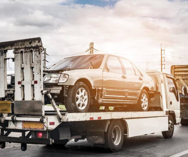 Unwanted car removal service towing old damaged car on truck