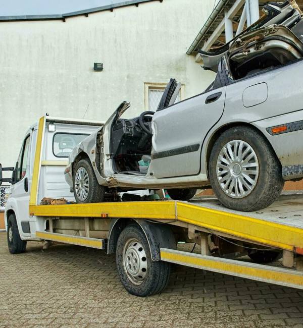 Unwanted car removal towing damaged vehicle on flatbed truck